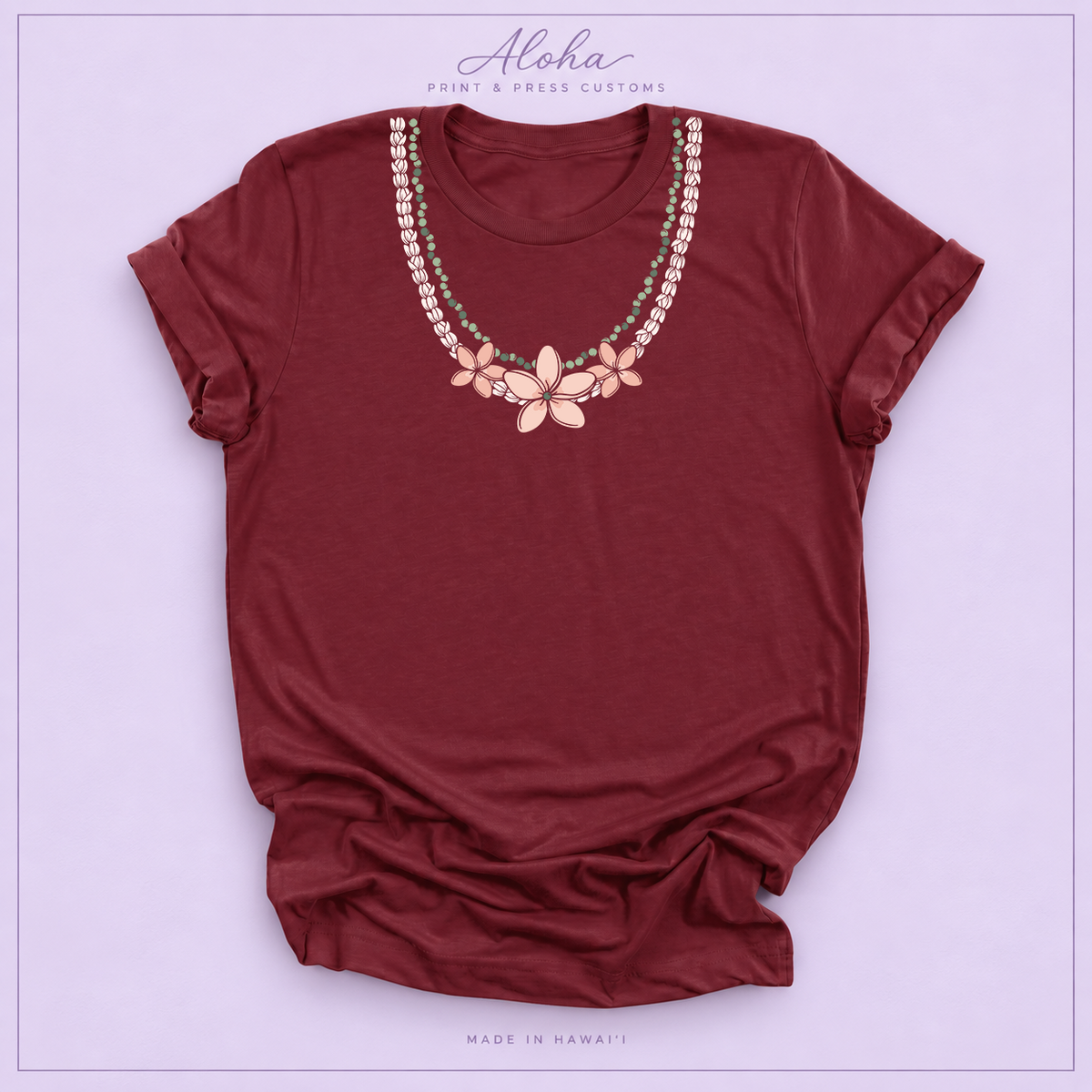 Maroon T-shirt with Pikake Mokihana Plumeria Hawaiian lei necklace design on Aloha Print & Press Customs branded background